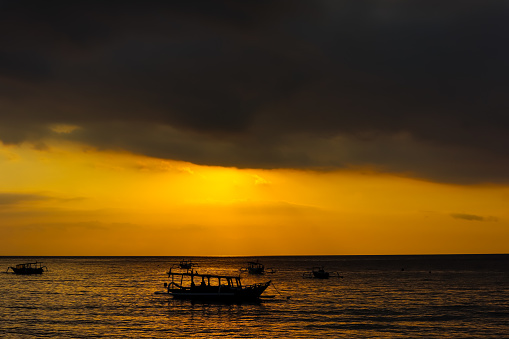 Silhouette view of traditional boats in the beach during sunset. Nipah beach, West Nusa Tenggara, Indonesian tourism object
