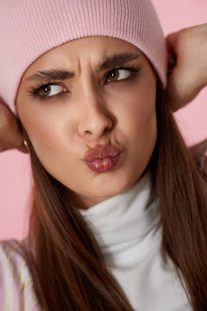 istock playful woman keeps hands on pink hat on pink background. 1691154915