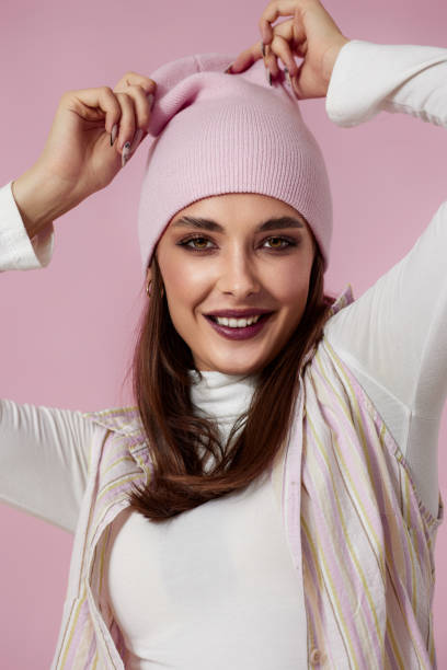 istock playful woman keeps hands on pink hat on pink background. 1691154950