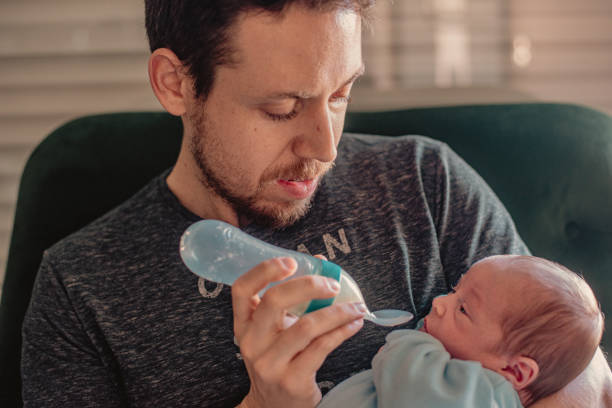 istock Father feeding his newborn baby with a silicone feeding bottle with spoon 1691158559