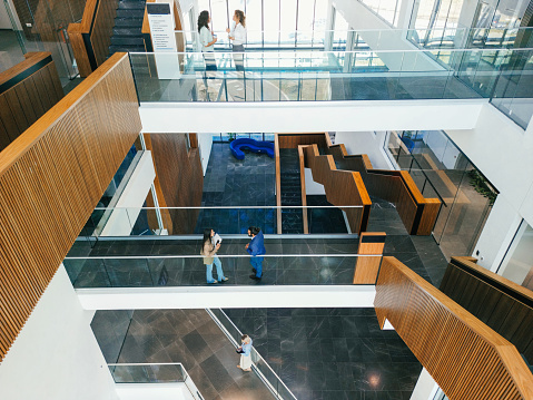 Confident and happy business people are walking and talking in office building hall corridor.