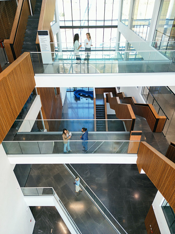 Confident and happy business people are walking and talking in office building hall corridor.