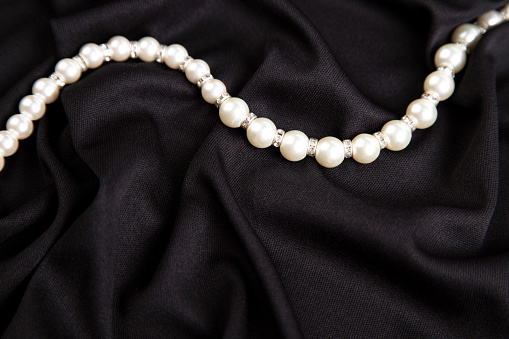 White pearl necklace on a dark background close up. Black and white