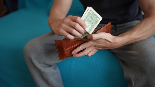 Young man holding wallet and counting money