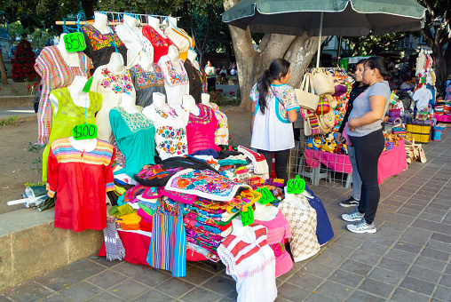 Oaxaca, Oaxaca de Juárez, A vendor with a customer at a stand of clothes in zocalo,  Editorial only.