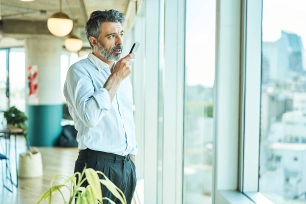 istock Male business professional talking on speaker phone standing in office 1691186507