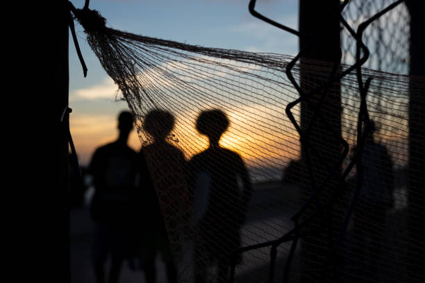 Sunset at the edge of a beach with people and objects silhouetted by a nylon net. Abstract photography concept.