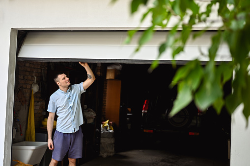 young adult man lifting gates of the garage.