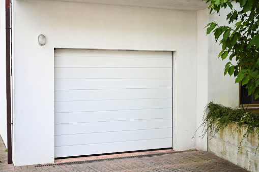 Panorama frame Two garage doors positioned at right angles sharing a paved forecourt in close up