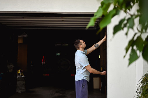 millennial man working with a gate in a garage.