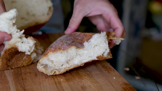 Caucasian man baker breaks bread into two parts. Close-up of a breaking white bread.