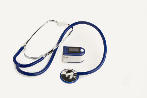 Portable finger heart pulse meter and a stethoscope on a white background