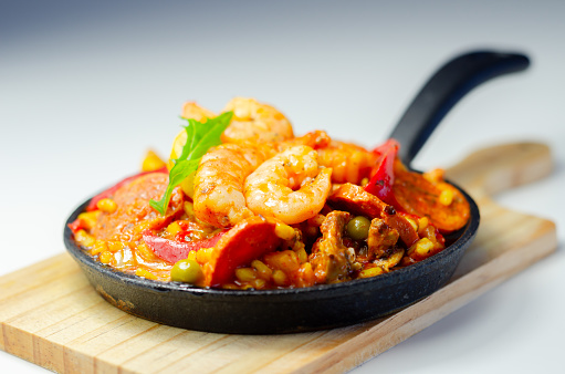 Delicious paella, cooked risotto rice with chicken thigh, king prawns, tomatoes and  chorizo, a traditional Spanish meal