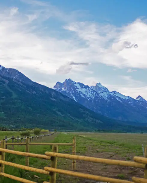 Photo of Majestic Grand Tetons at Sunset: Snow-Dusted Peaks and Rustic Fence Posts