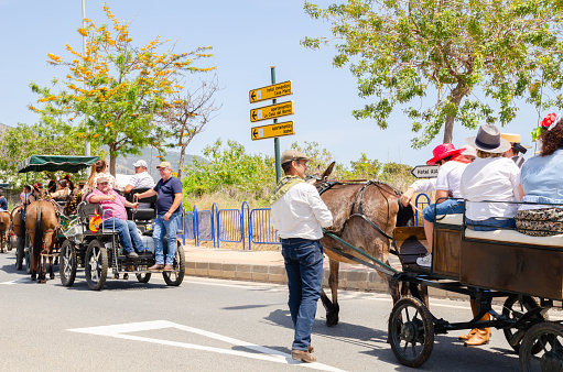 NERJA, SPAIN - 15 MAY 2022 City residents, carriages, carts, horses, oxen and tractors, as well as local farmers coming from neighbouring villages all dressed in the best and most beautiful traditional folk costumes