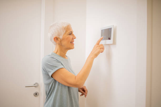 istock Young woman adjusts the temperature at home with a device on the wall 1691409245