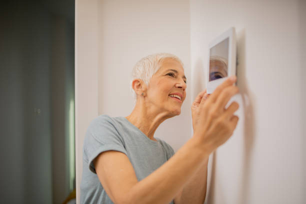 istock Young woman adjusts the temperature at home with a device on the wall 1691409251