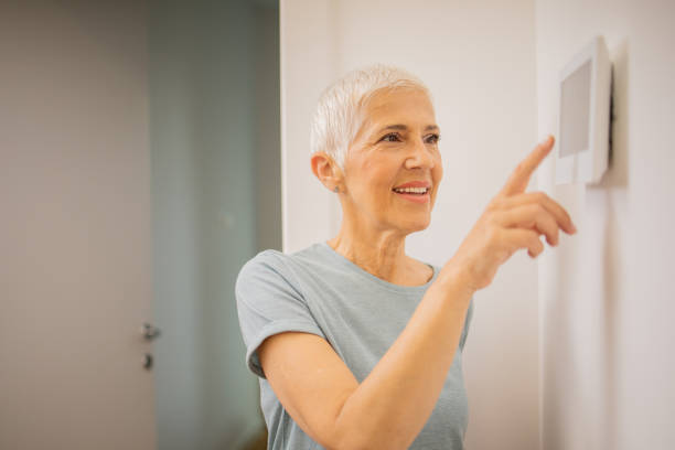 istock Young woman adjusts the temperature at home with a device on the wall 1691409252