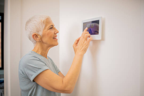 istock Young woman adjusts the temperature at home with a device on the wall 1691409254