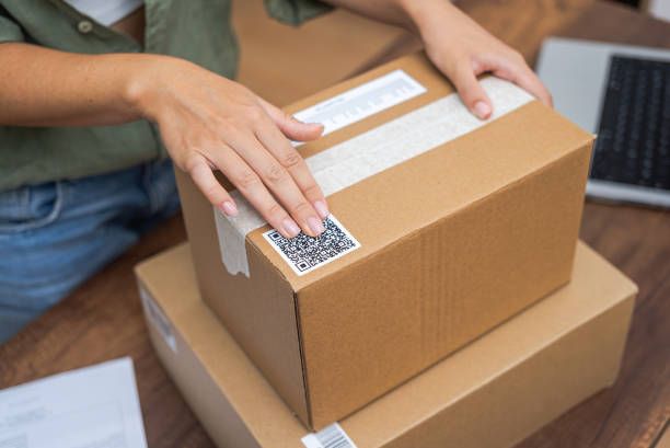 istock Woman post office worker works sticking barcode on cardboard box for sending goods to recipient 1691409362