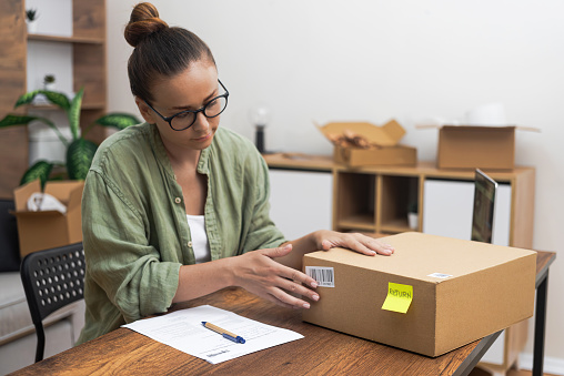 young woman's commitment as she sits at her table, using her laptop and writing a return order, expressing her desire to return a product.