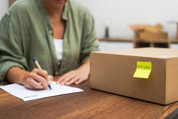 istock Female writes complaint about delivery near parcel with yellow sticker with word Return on desk 1691410046