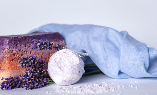 Spa massage setting with lavender flowers, soap and cosmetic salt on wooden background. SPA salon and beauty concept with warm light. Close up. Copy space.