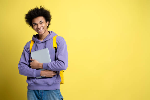 istock Smiling African American student holding laptop isolated on yellow background, copy space 1691437228