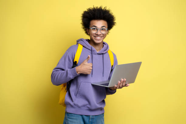 istock Smiling African American man freelancer using laptop holding thumb up isolated on yellow background 1691437232