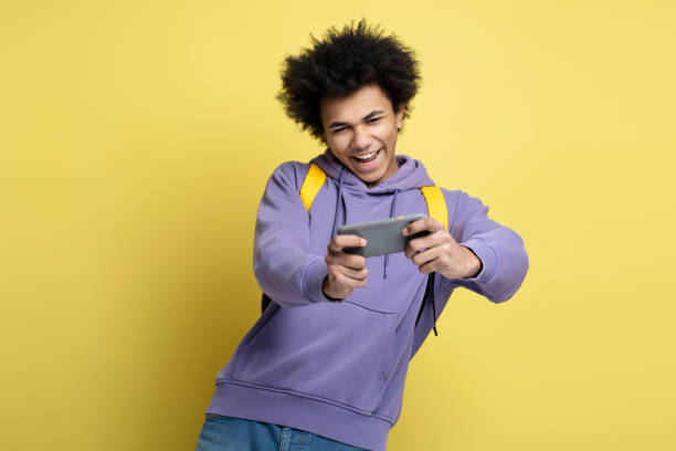 istock Overjoyed African American man holding smartphone playing mobile game isolated on yellow background 1691437247