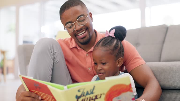 Reading, father and story with girl for learning in lounge for education or quality time. Kid, books and parent for support on floor or fun with growth for child development in home with family.