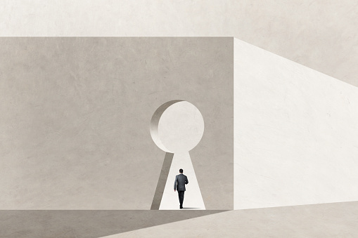 A man walks through a large keyhole in a building that represents opportunity\n.