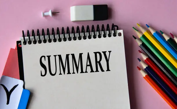 SUMMARY - a word written in a notebook on a pink background and colored pencils