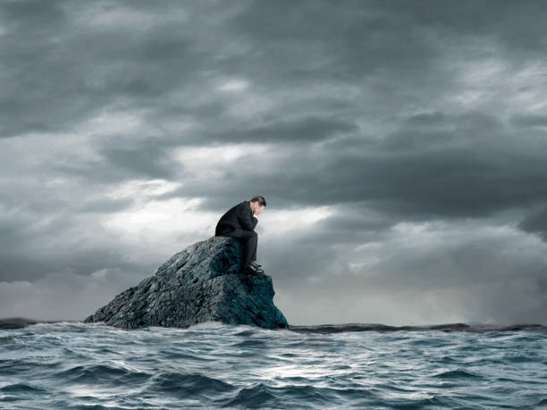 uomo bloccato su una piccola roccia nell'oceano - storm sea business uncertainty foto e immagini stock