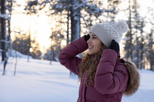 Portrait of a happy woman outdoors enjoying the snow and wearing winter clothes - travel destinations