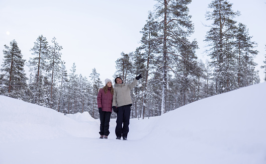 Loving couple taking a walk outdoors while enjoying their winter honeymoon in Finland