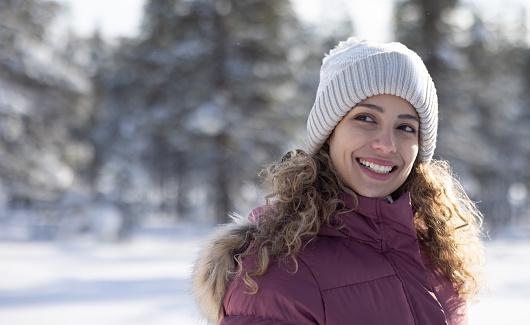 Portrait of a beautiful woman enjoying the winter outdoors in Finland and looking away smiling - lifestyle concepts