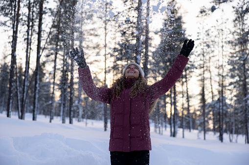 Happy woman outdoors playing with the snow and enjoying the winter - travel destinations concepts