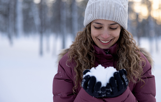 Portrait of a happy woman playing with the snow while enjoying the winter and holding a snowball