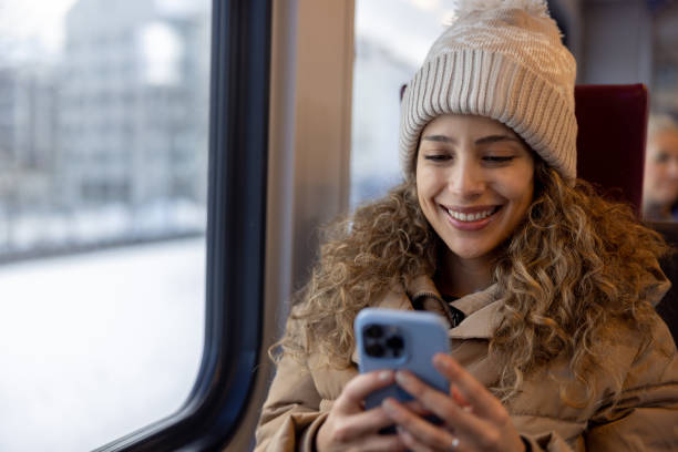 istock Happy woman riding the train in the winter while using her phone 1691534207