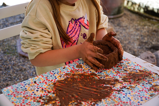 A close-up view of a girl's hands playing with clay