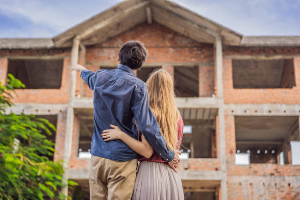 istock Couple looking at their new house under construction, planning future and dreaming. Young family dreaming about a new home. Real estate concept 1691554195