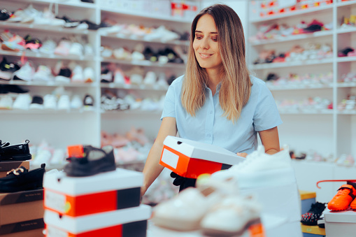 Shop Assistant Arranging Shoe Boxes in Footwear Store