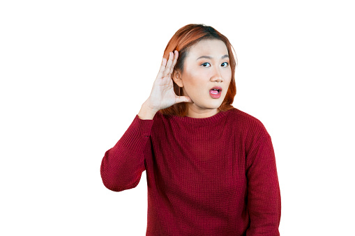 Young curious nosy woman of Asian ethnicity 20s wearing red sweater try to hear you overhear listening isolated over white