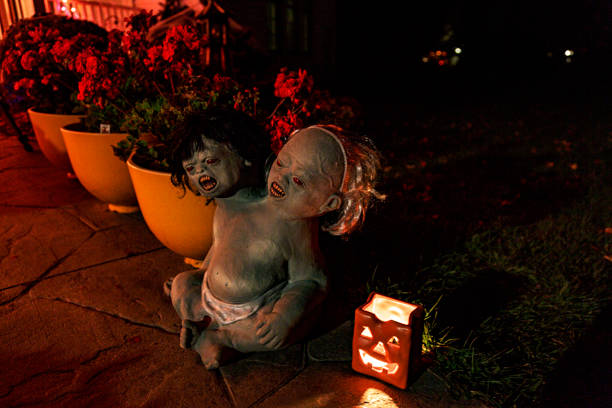 A set of furious, raging conjoined twin Halloween character horror dolls sitting at the edge of a dark, spooky Halloween trick or treat walkway.