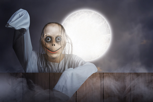 Scary Momo standing behind the wooden fence with a night scene background. Scary face for Halloween. Halloween concept