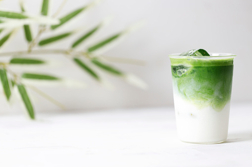 Green tea latte, Japanese iced matcha latte, with whipped green tea and milk on white wooden table.