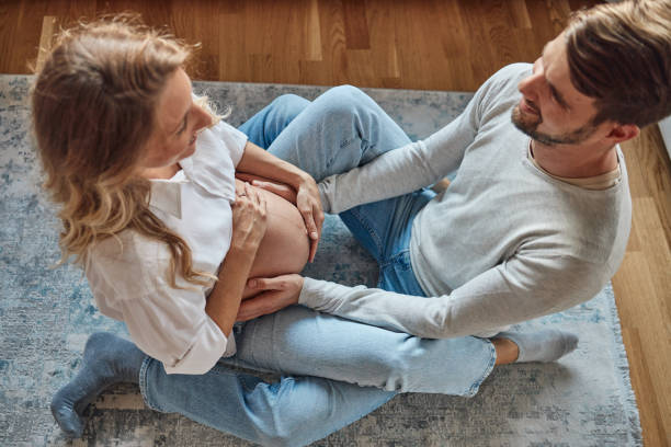 hermosa pareja abrazando el vientre embarazada de la mujer - two parent family naked men couple fotografías e imágenes de stock