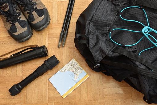 High angle view of travel equipment with shoes, backpack, lamp and map