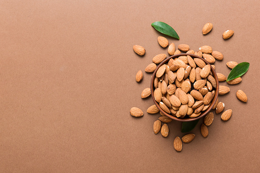 Fresh healthy Almond in bowl on colored table background. Top view.